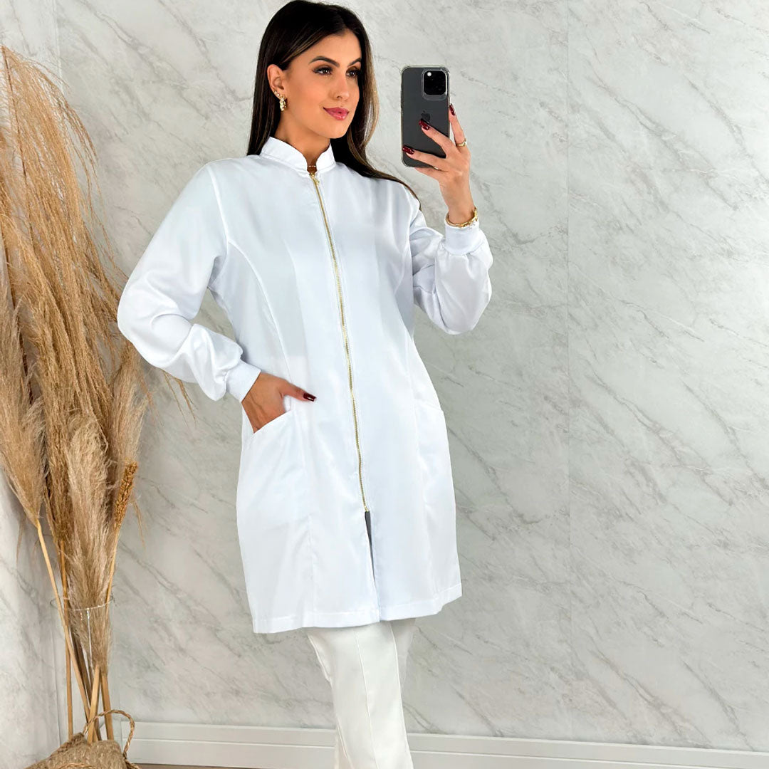 Jaleco feminino de manga longa com punhos, gola padre e zíper frontal dourado. Modelo acinturado em tecido gabardine com bolsos laterais. Disponível nas cores branca e preta.