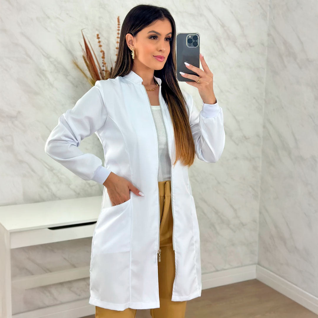 Jaleco feminino de manga longa com punhos, gola padre e zíper frontal dourado. Modelo acinturado em tecido gabardine com bolsos laterais. Disponível nas cores branca e preta.