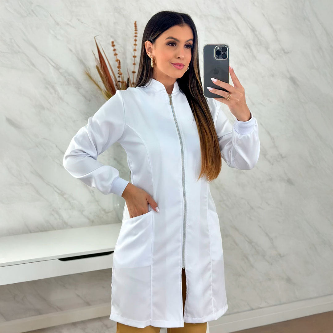 Jaleco feminino de manga longa com punhos, gola padre e zíper frontal dourado. Modelo acinturado em tecido gabardine com bolsos laterais. Disponível nas cores branca e preta.