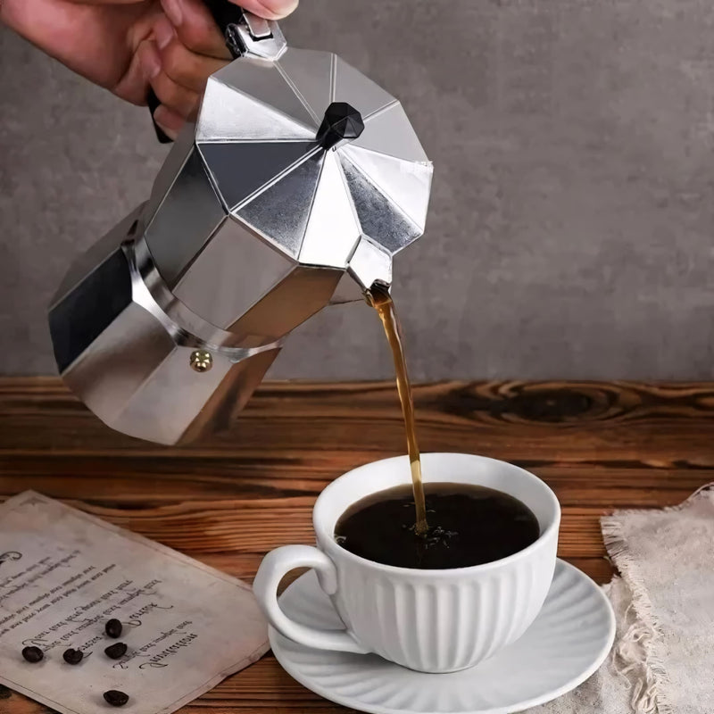 Cafeteira italiana clássica em alumínio polido, com cabo ergonômico preto. Prepara café encorpado no fogão, disponível em tamanhos de 3, 6 ou 9 xícaras. Ideal para um café artesanal com aroma intenso.