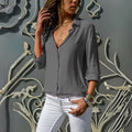 Mulher usando camisa feminina de tecido leve e caimento solto, com manga longa dobrada. Peça elegante e versátil, ideal para looks casuais e formais com conforto e sofisticação.