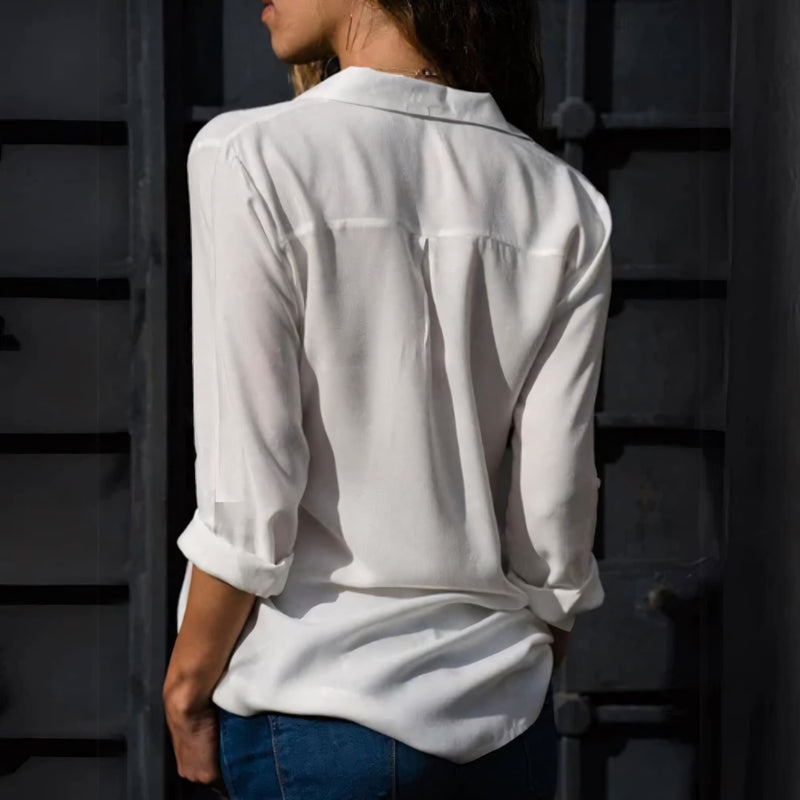 Mulher usando camisa feminina de tecido leve e caimento solto, com manga longa dobrada. Peça elegante e versátil, ideal para looks casuais e formais com conforto e sofisticação.