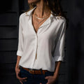 Mulher usando camisa feminina de tecido leve e caimento solto, com manga longa dobrada. Peça elegante e versátil, ideal para looks casuais e formais com conforto e sofisticação.