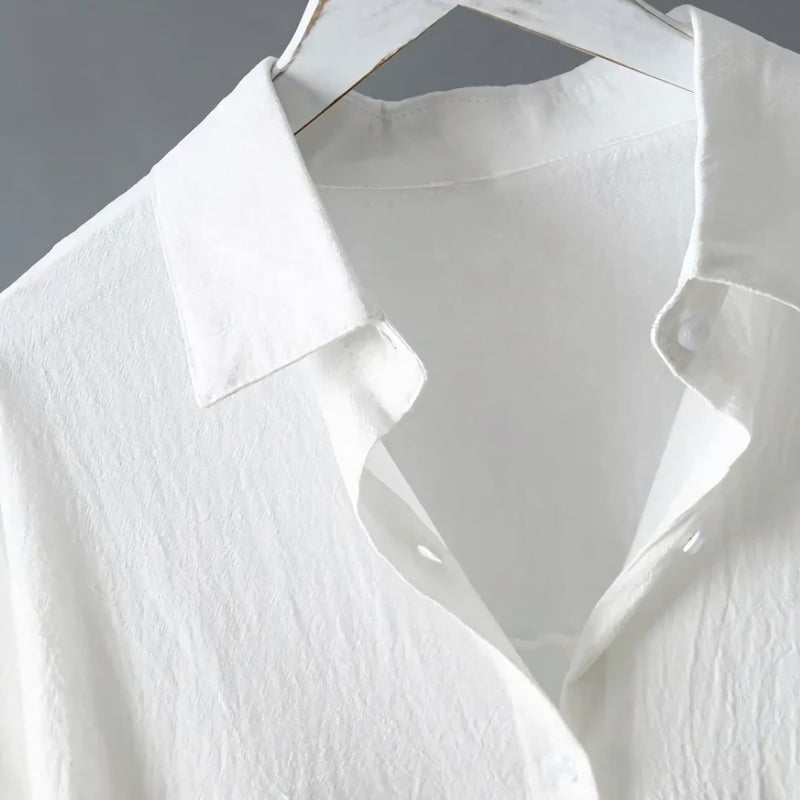 Modelo veste o Chemise Natural Serena em tom claro, com caimento leve, manga longa dobrada e visual minimalista. Ideal para looks casuais, de verão ou urbanos, com toque suave do linho e conforto respirável.