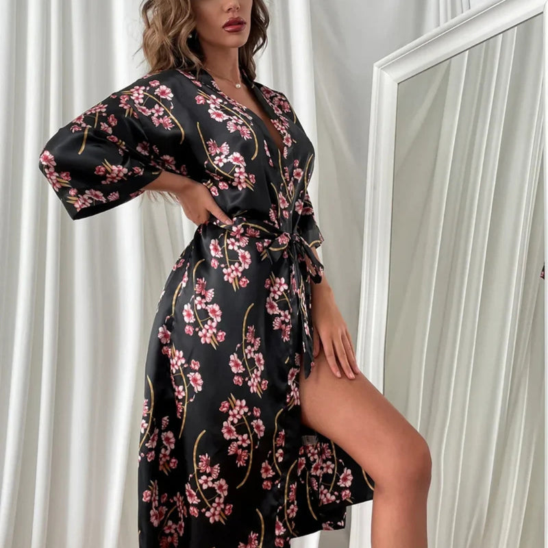 Modelo usando robe floral feminino em cetim preto e amarelo, com estampa de flores delicadas, faixa na cintura e caimento leve, ideal para momentos de autocuidado e elegância.