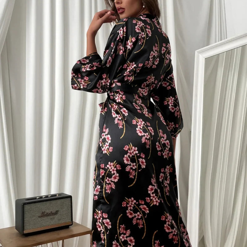 Modelo usando robe floral feminino em cetim preto e amarelo, com estampa de flores delicadas, faixa na cintura e caimento leve, ideal para momentos de autocuidado e elegância.