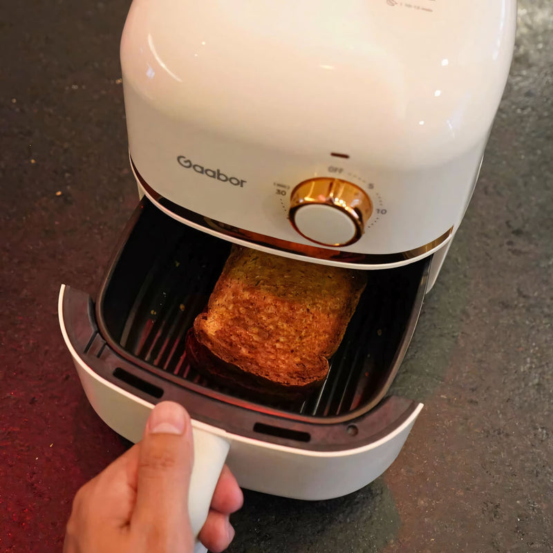 Fritadeira elétrica Gaabor com 1,4 litros, acabamento sofisticado em creme com detalhes dourados, timer analógico e tecnologia Cyclone Air para receitas crocantes sem óleo.