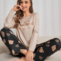 Mulher usando pijama longo feminino com blusa bege e calça preta estampada com rostos de ursinhos e corações, ideal para conforto e estilo em noites amenas.