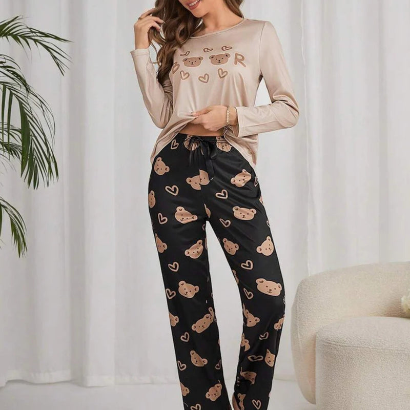 Mulher usando pijama longo feminino com blusa bege e calça preta estampada com rostos de ursinhos e corações, ideal para conforto e estilo em noites amenas.