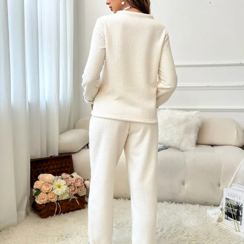 Mulher usando o Pijama Longo Chalten, modelo em tecido canelado branco com bordado de coroa, ideal para noites frias e momentos de conforto elegante.