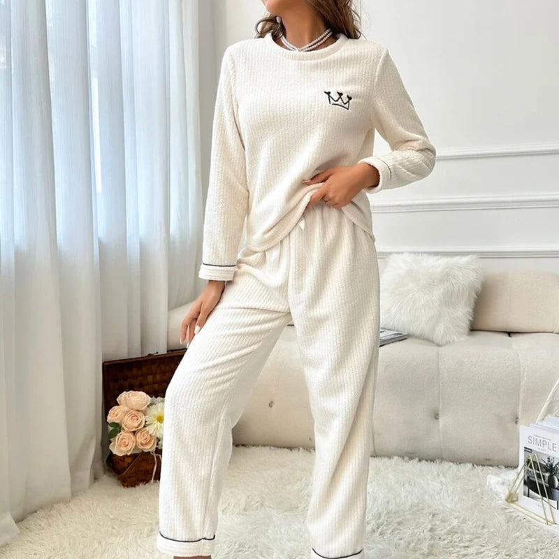 Mulher usando o Pijama Longo Chalten, modelo em tecido canelado branco com bordado de coroa, ideal para noites frias e momentos de conforto elegante.