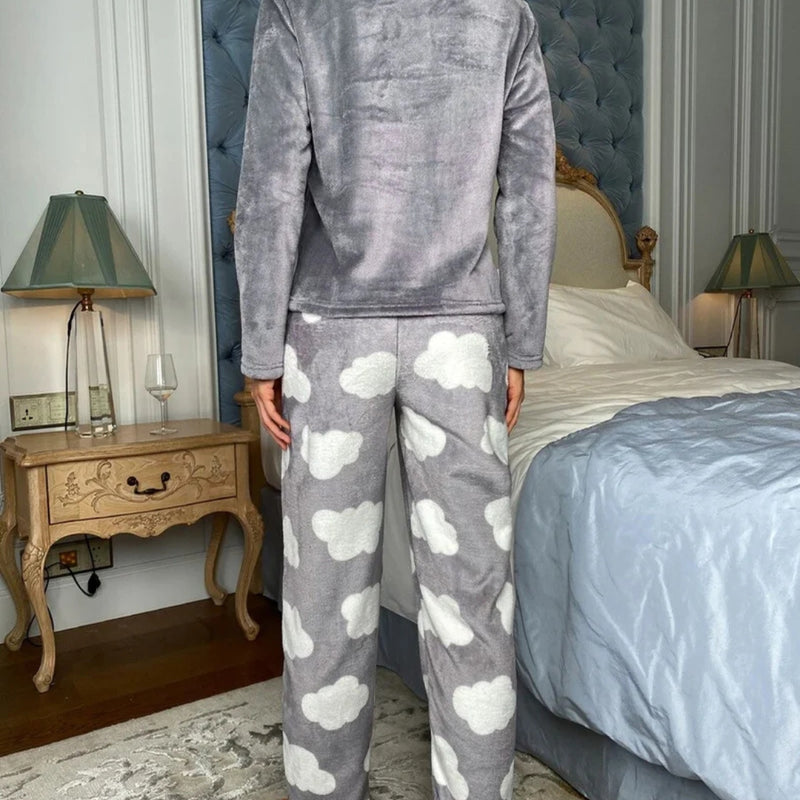 Mulher vestindo o Pijama Longo Cílios em tecido peluciado com estampa de nuvem e bordado de cílios nos olhos, ideal para noites frias e cheias de conforto.

