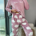 Mulher vestindo o Pijama Longo Cílios em tecido peluciado com estampa de nuvem e bordado de cílios nos olhos, ideal para noites frias e cheias de conforto.

