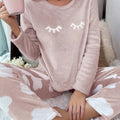 Mulher vestindo o Pijama Longo Cílios em tecido peluciado com estampa de nuvem e bordado de cílios nos olhos, ideal para noites frias e cheias de conforto.

