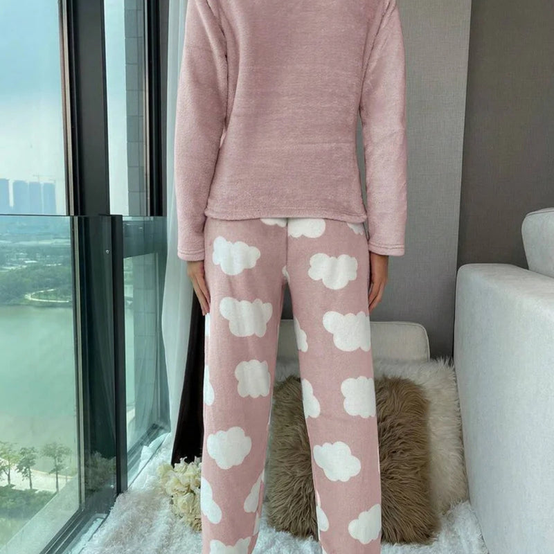 Mulher vestindo o Pijama Longo Cílios em tecido peluciado com estampa de nuvem e bordado de cílios nos olhos, ideal para noites frias e cheias de conforto.

