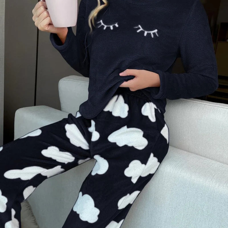 Mulher vestindo o Pijama Longo Cílios em tecido peluciado com estampa de nuvem e bordado de cílios nos olhos, ideal para noites frias e cheias de conforto.

