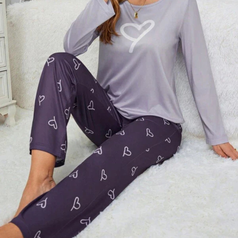 Pijama longo feminino com blusa rosa claro e estampa de coração branco. Acompanha calça preta com desenhos de coração e ajuste em laço. Conforto com romantismo.

