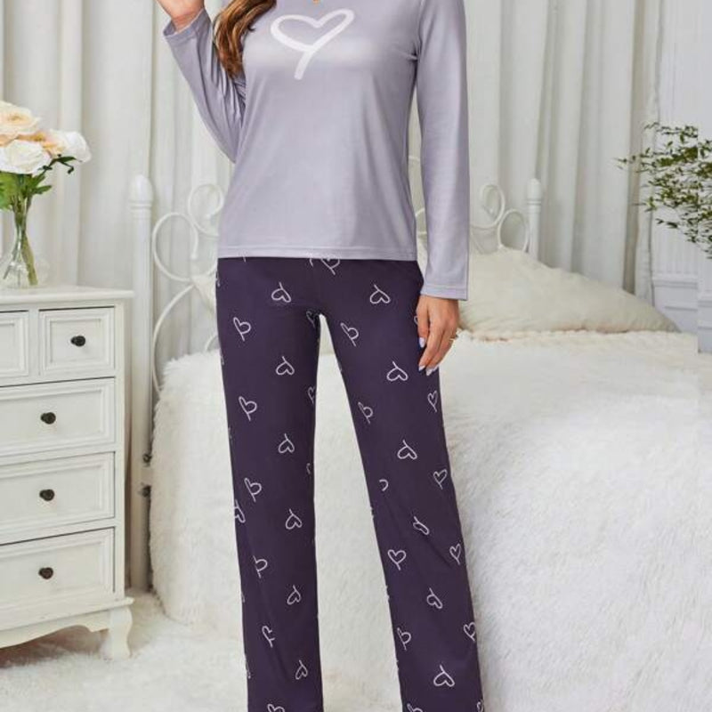 Pijama longo feminino com blusa rosa claro e estampa de coração branco. Acompanha calça preta com desenhos de coração e ajuste em laço. Conforto com romantismo.

