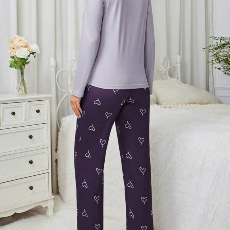 Pijama longo feminino com blusa rosa claro e estampa de coração branco. Acompanha calça preta com desenhos de coração e ajuste em laço. Conforto com romantismo.

