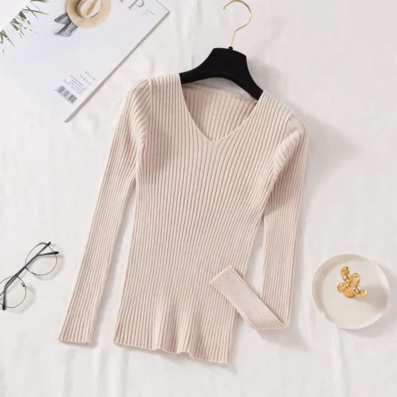 Suéter feminino em tricot canelado com gola V, manga longa e modelagem ajustada. Ideal para dias frios, combina com jeans, alfaiataria e looks casuais elegantes.