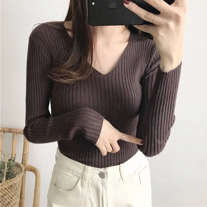 Suéter feminino em tricot canelado com gola V, manga longa e modelagem ajustada. Ideal para dias frios, combina com jeans, alfaiataria e looks casuais elegantes.