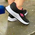 Tênis feminino fitness disponível nas cores preta com rosa, preta com branco e cinza com rosa. Modelo esportivo com cabedal respirável e solado alto emborrachado, ideal para treinos, caminhadas e o dia a dia.